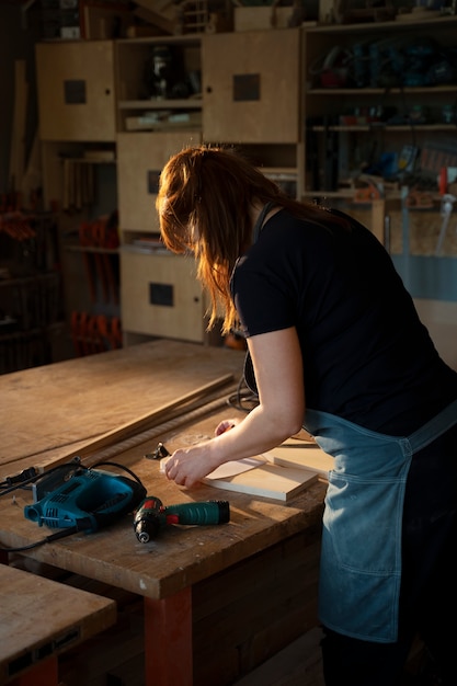 Free Photo side view female carpenter working in atelier