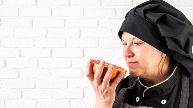 Side view of female chef smelling grapefruit