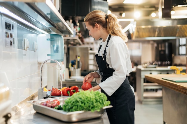 Side view of female chef washing vegetables in the kitchen