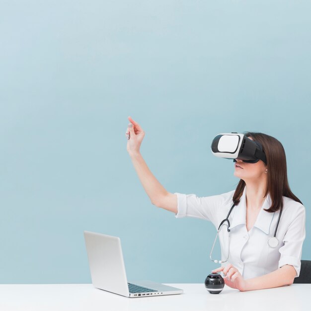 Side view of female doctor with stethoscope using virtual reality headset