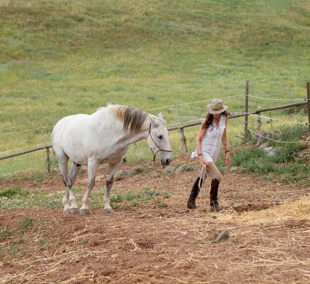 Free photo side view of female farmer with her horse outdoors