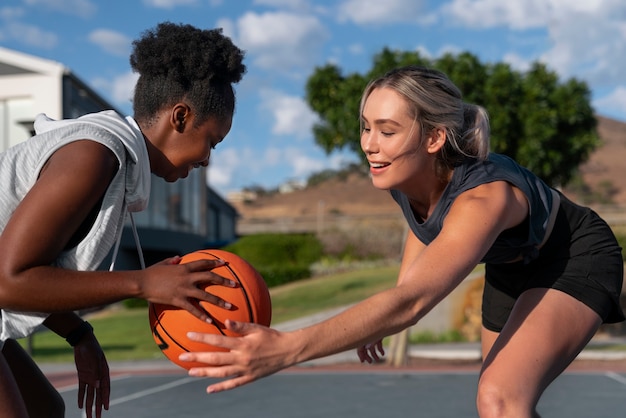 Side view female friends playing basketball