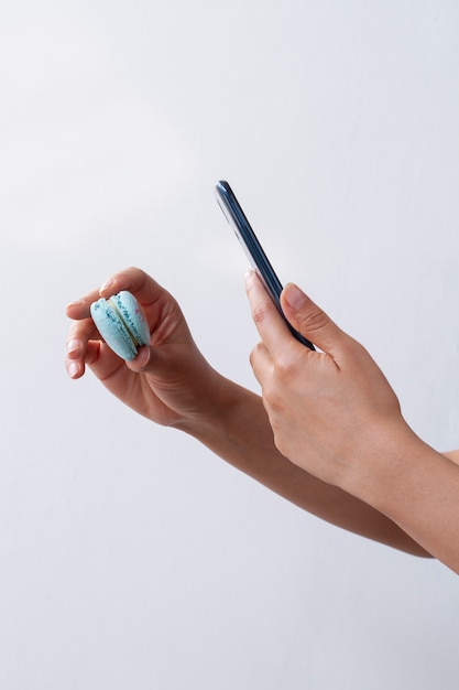 Side view of female hands taking photo of macaron