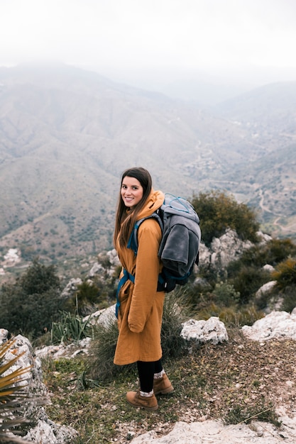 Free photo side view of a female hiker with her backpack hiking on mountains