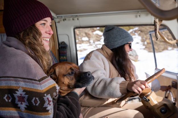 Free photo side view of female lovers with their dog during winter trip