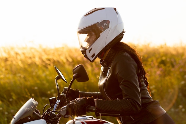 Free photo side view female motorcycle rider with helmet