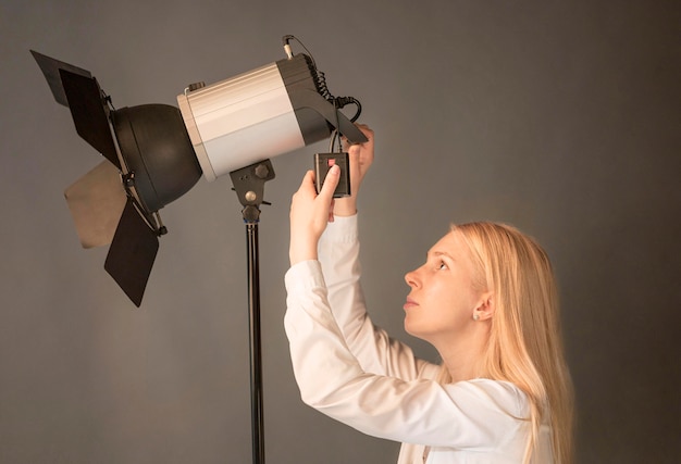 Free Photo side view female photographer adjusting the lamp