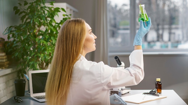 Side view of female researcher with gloves in the laboratory holding test tube