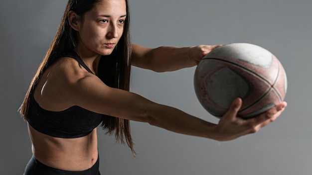 Side view of female rugby player posing with ball