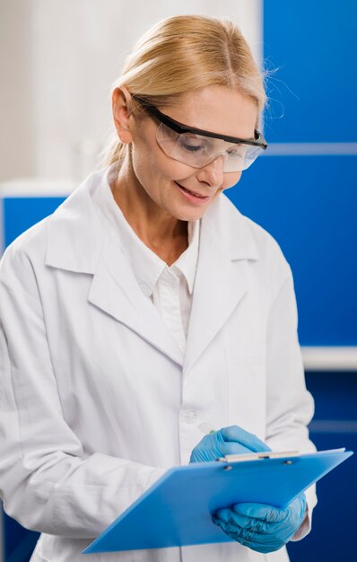 Side view of female scientist with surgical gloves writing something