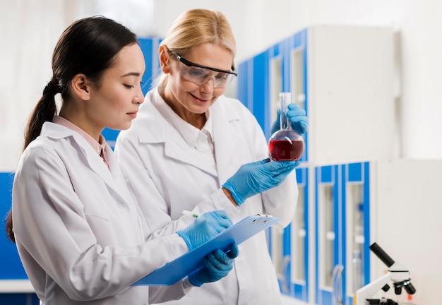 Free photo side view of female scientists analyzing substance in the lab