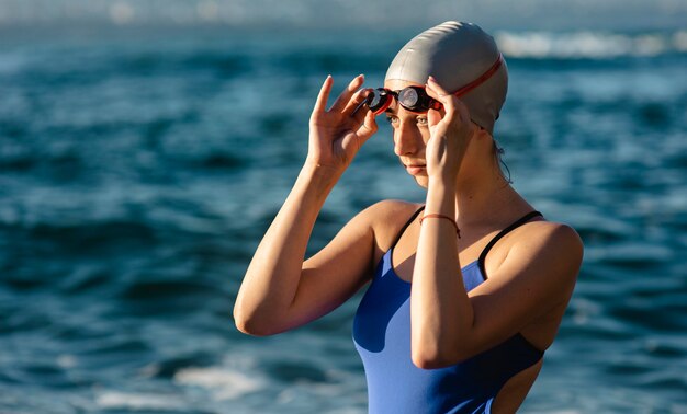 Side view of female swimmer with swimming goggles and cap