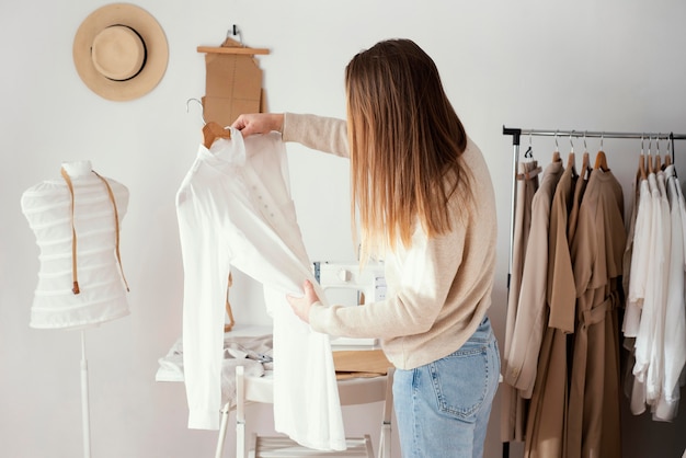 Free photo side view of female tailor checking garments