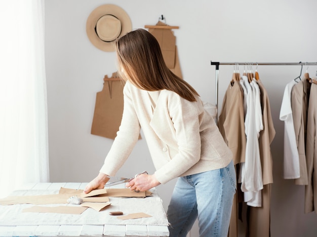 Side view of female tailor in the studio with clothes