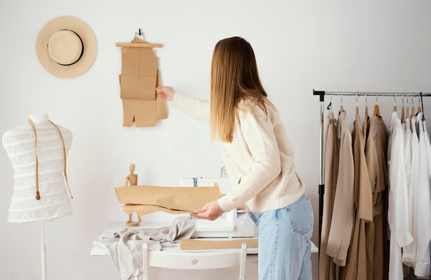 Free photo side view of female tailor working on patterns in the studio