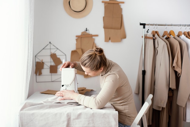 Side view of female tailor working in the studio with sewing machine