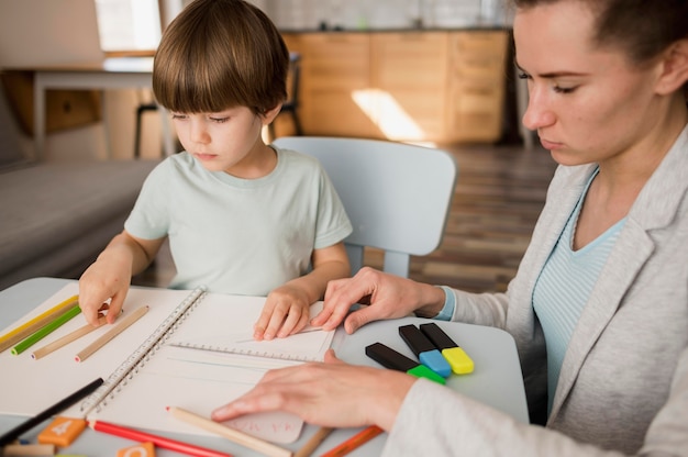 Side view of female tutor teaching child at home