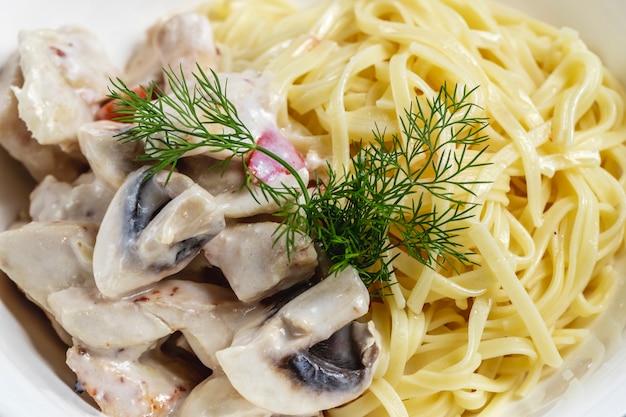 Side view fettuccini alfredo with grilled mushrooms sauce and dill on a plate