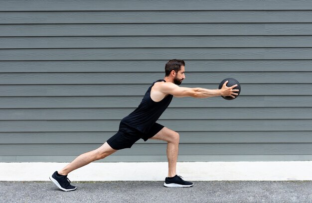 Side view fit man training with ball