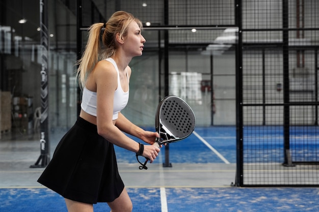 Side view fit woman playing paddle tennis