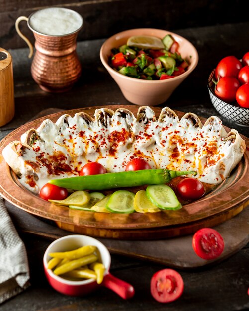 Side view of flatbread kebab doner slices garnished with yogurt and served with vegetables