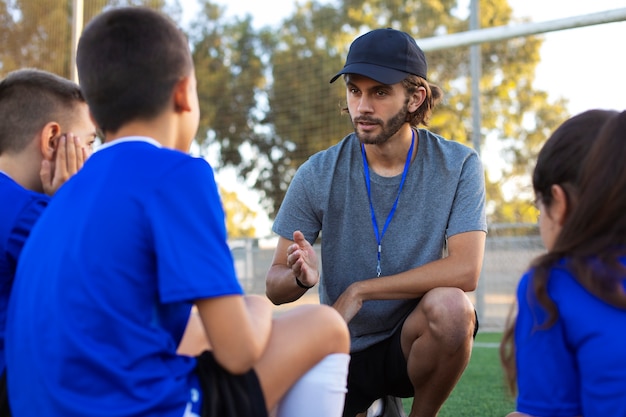 Side view football trainer helping kids