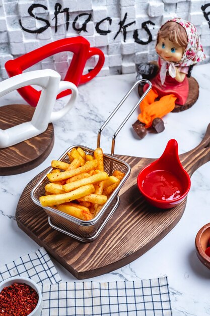 Side view french fries in a basket with ketchup on the board