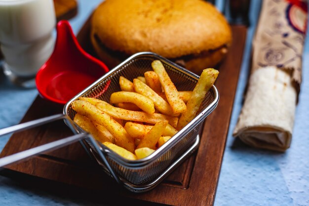 Side view french fries with ketchup and burger on a board