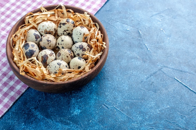 Side view of fresh poultry chicken farm eggs in a tissue basket in a brown bowl on purple stripped towel on the right side on blue background