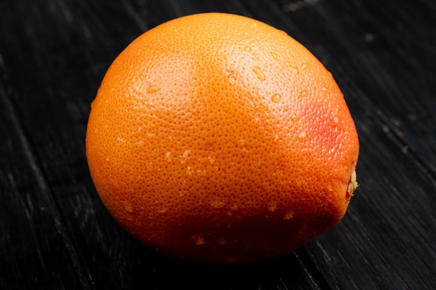 side view of fresh ripe grapefruit with water drops isolated on black surface