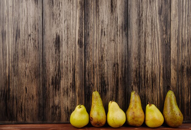 Side view of fresh ripe pears in a line on a wooden background with copy space