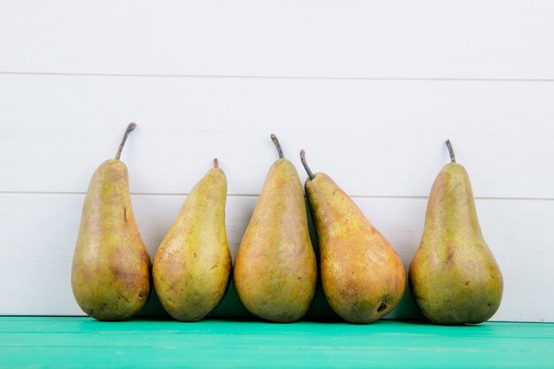 Side view of fresh ripe pears on white wooden background