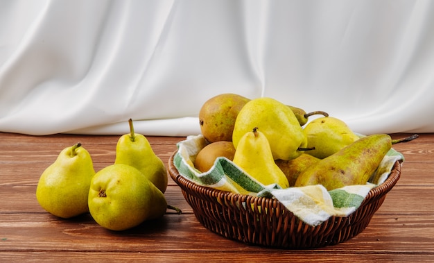 Free photo side view of fresh ripe pears in a wicker basket on a wooden background