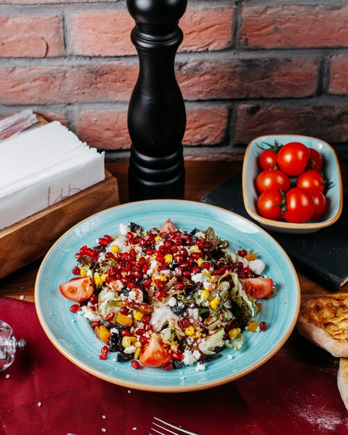 Side view of fresh salad with cabbage tomatoes white cheese and pomegranate seeds on a plate