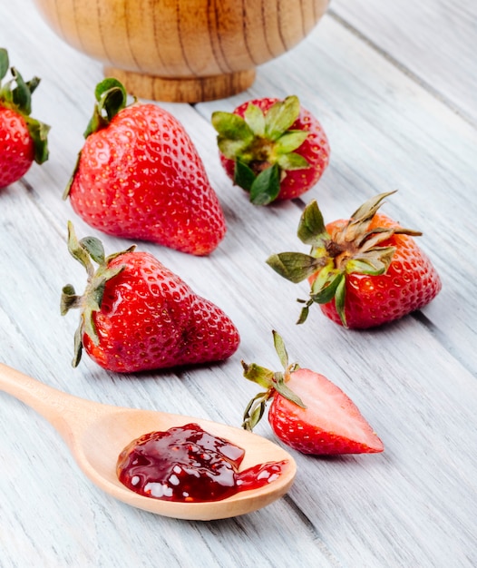 Side view fresh strawberry and jam on white wooden background