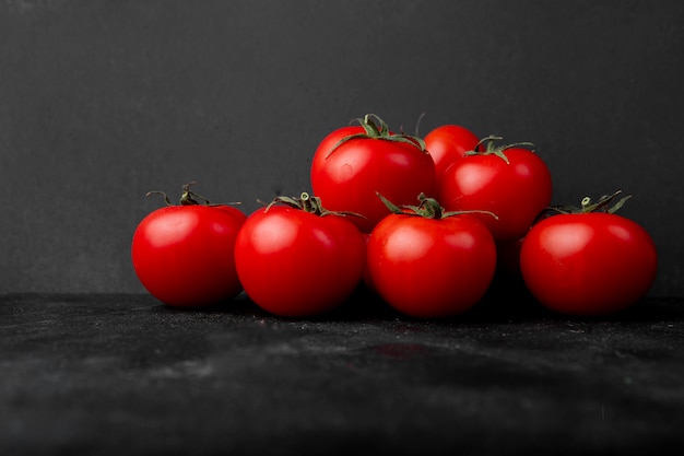 Side view of fresh tomatoes on black background