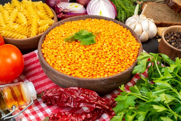 Side view of fresh vegetables bread slices red lentils in a brown bowl pepper pastas