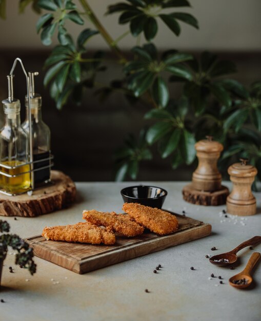 Side view of fried chicken fillet in bread crumb on a wooden board