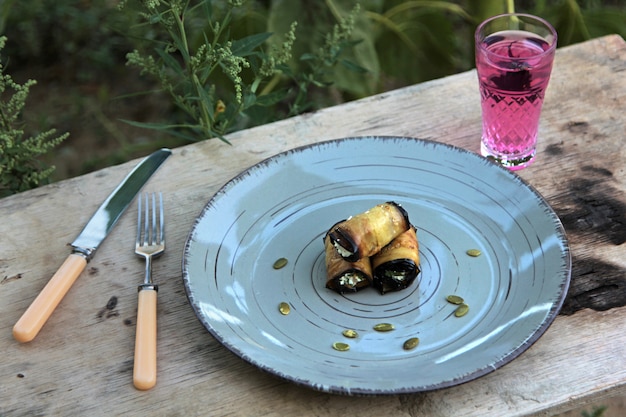 Free photo side view of fried eggplant roll with cream cheese garlic and nuts on plate outdoor