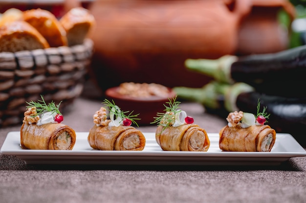 Side view of fried eggplant rolls with nuts and garlic  decorated with dill on the table