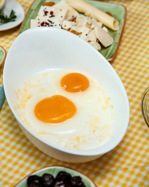 Free photo side view of fried eggs on kitchen table