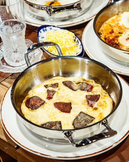 Side view of fried eggs with sausage in a pan