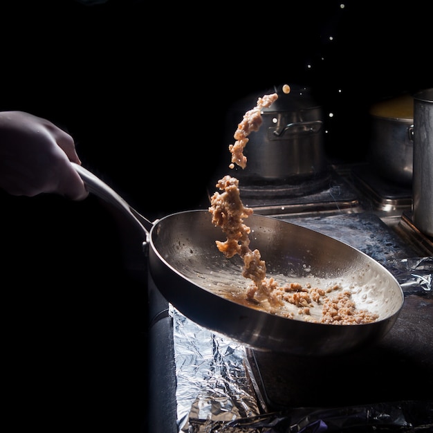 Side view fried minced with pan and human hand in stove