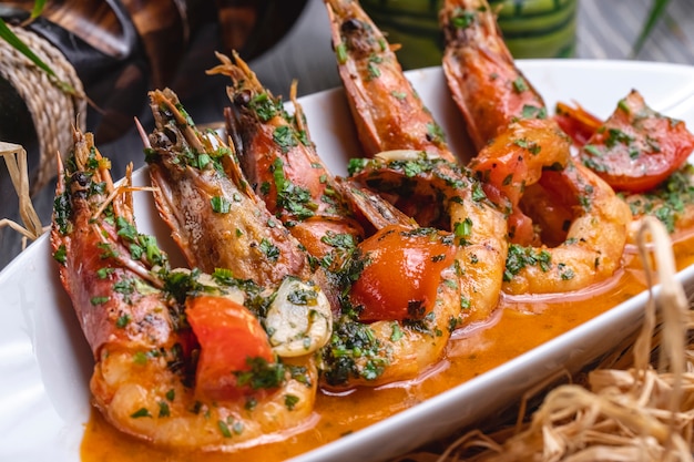 Free photo side view fried shrimps in sauce with tomatoes and herbs