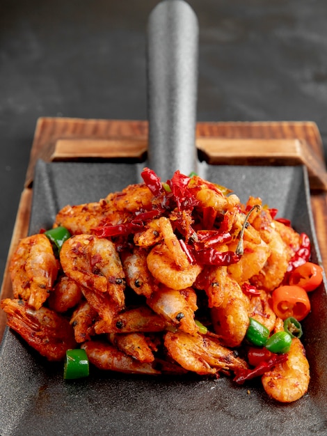 Free Photo side view of fried shrimps with red and green peppers on a wooden cutting board