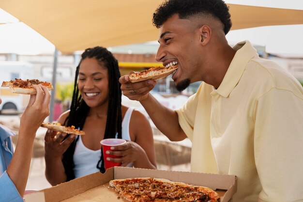 Side view friends eating pizza