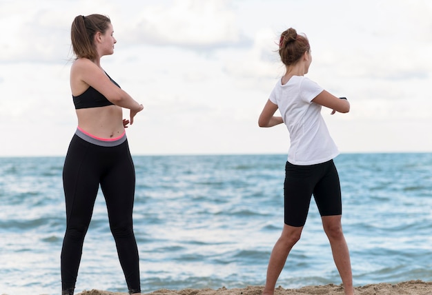 Side view friends exercising at beach