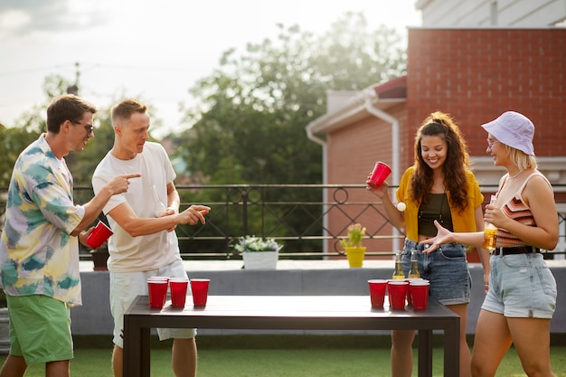 Free photo side view  friends playing beer pong