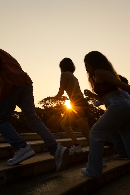 Side view friends silhouettes running at sunset