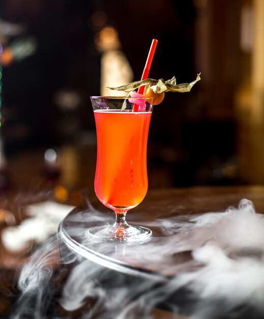 Side view fruit drink with physalis and straw in the glass